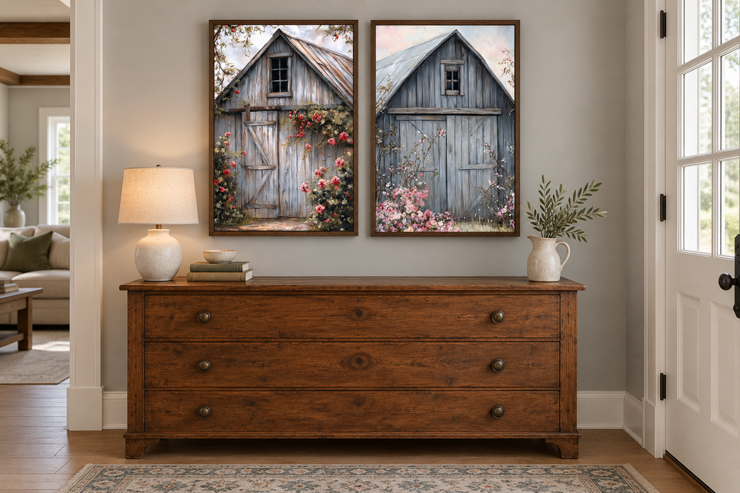Two framed canvas paintings of rustic grey barn doors with pink flowers above a wooden dresser.