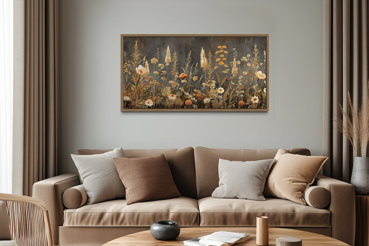 Grey and beige boho wildflowers field framed canvas wall art hanging above a brown sofa.