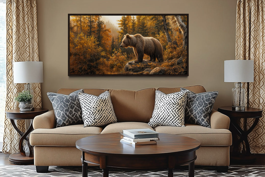 Framed canvas wall art of a grizzly bear in a golden autumn forest above a brown sofa.