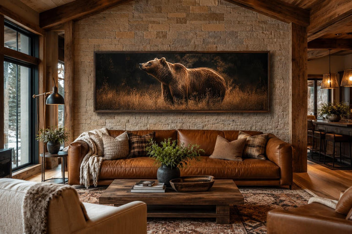 Rustic horizontal canvas art of a grizzly bear in golden grass above a leather sofa in a cabin.