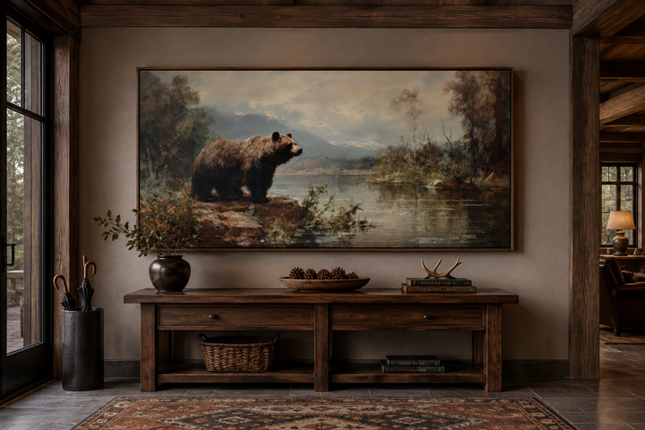 Framed grizzly bear canvas print above a rustic wooden console table in a cabin-style entryway.