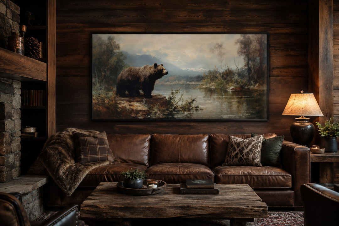 Framed grizzly bear canvas print on a dark wood wall above a brown leather sofa in a rustic cabin.