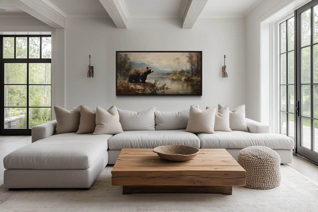 Framed grizzly bear canvas print on a white wall above a modern sectional sofa in a rustic room.