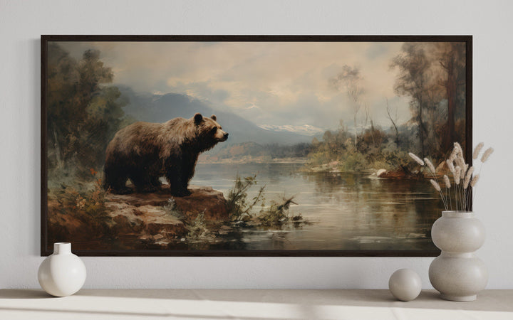 Framed canvas print of a grizzly bear standing by a river in a rustic mountain landscape.