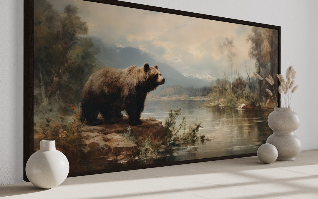 Framed grizzly bear canvas print on a riverbank, rustic cabin wildlife wall art for home decor.