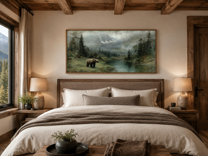 Rustic framed canvas wall art of a grizzly bear by a mountain lake above a bed in a cabin bedroom.