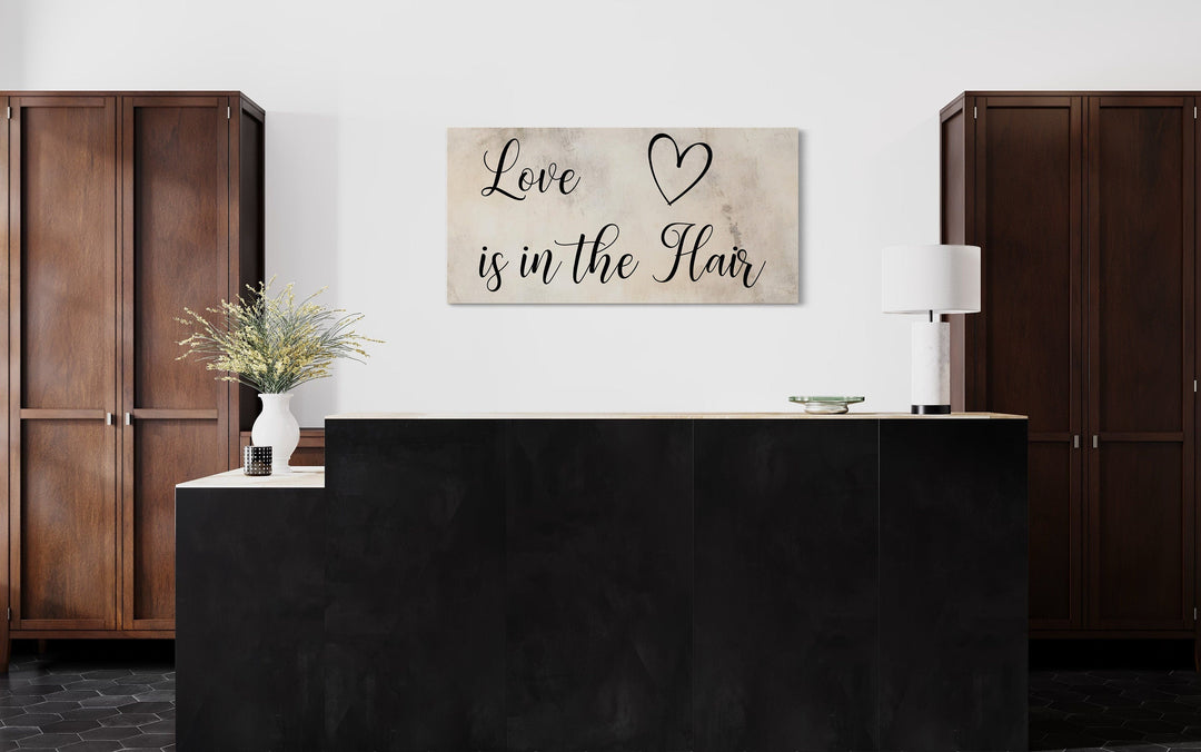 Chic canvas wall art with 'Love is in the Hair' typography above a salon reception desk.