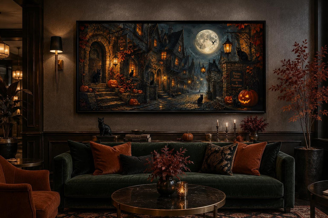Halloween Village canvas art with a black cat, full moon, and pumpkins above a green velvet sofa.