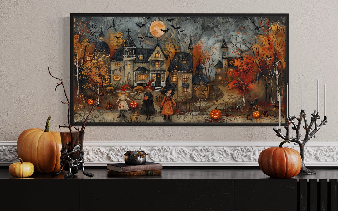 Framed canvas art of children trick-or-treating in a whimsical village with pumpkins and a full moon.