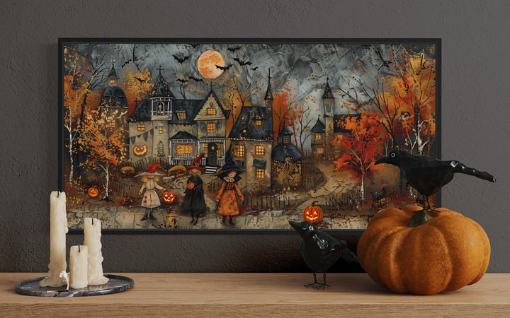 Framed Halloween canvas art of children trick-or-treating in a whimsical village with pumpkins.