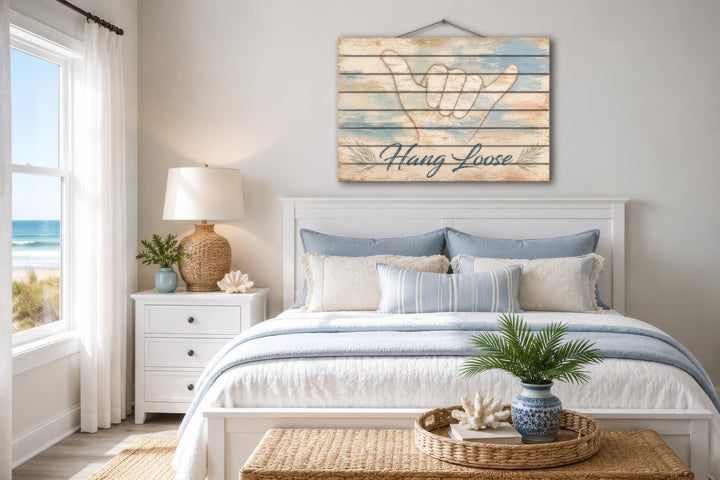 Hang Loose Shaka Sign distressed wood wall art hanging above a bed in a coastal-themed bedroom.