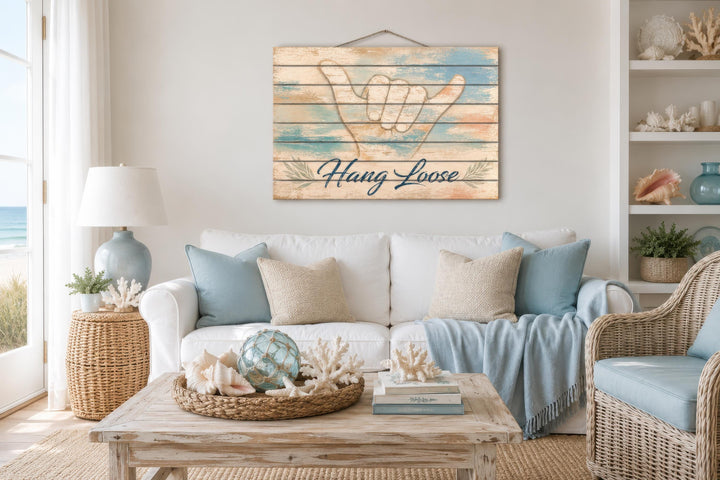 Hang Loose Shaka Sign distressed wood wall art hanging above a white sofa in a coastal living room.
