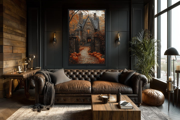 Haunted house and pumpkin path Halloween canvas art hanging in a dark, moody living room.