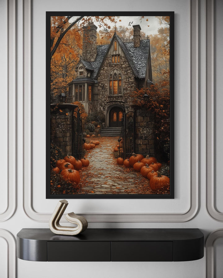 Haunted house canvas art with a pumpkin-lined stone path, displayed above a black console table.