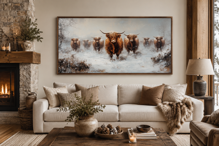 Herd of Highland cows in snow framed canvas wall art hanging above a sofa in a rustic living room.