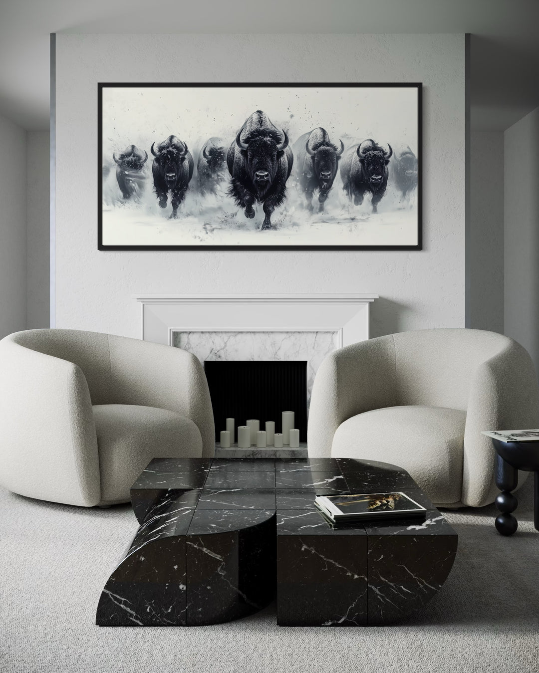 Black and white framed canvas wall art of a herd of bison running through snow above a fireplace.