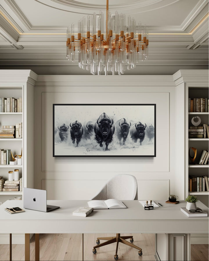 Black and white framed canvas wall art of a bison herd running through snow in a modern office.