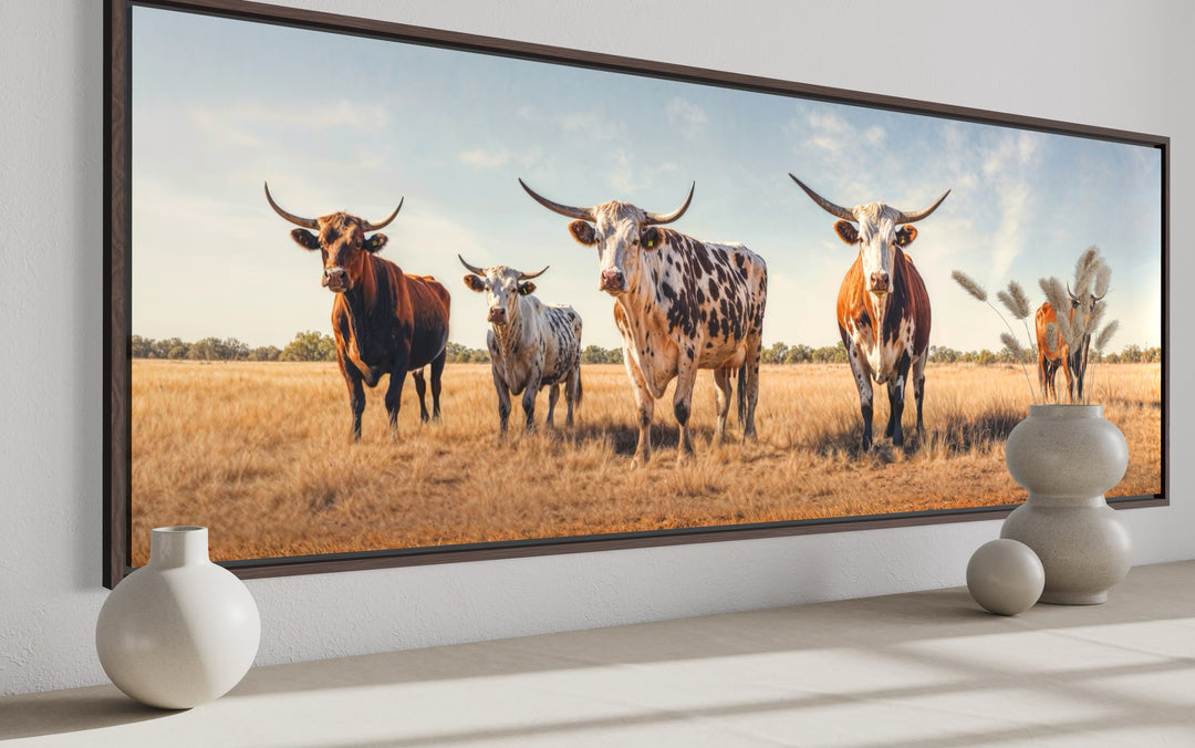 Panoramic framed canvas wall art featuring a herd of Texas Longhorn cows in a golden field.