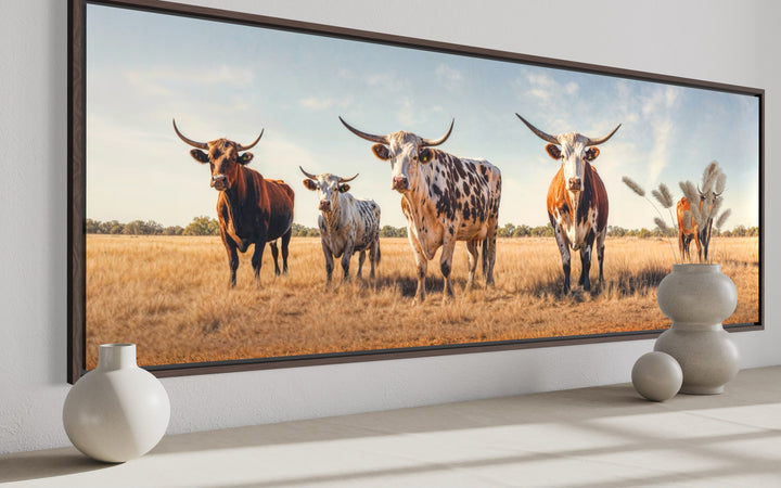 Panoramic framed canvas wall art featuring a herd of Texas Longhorn cows in a golden field.