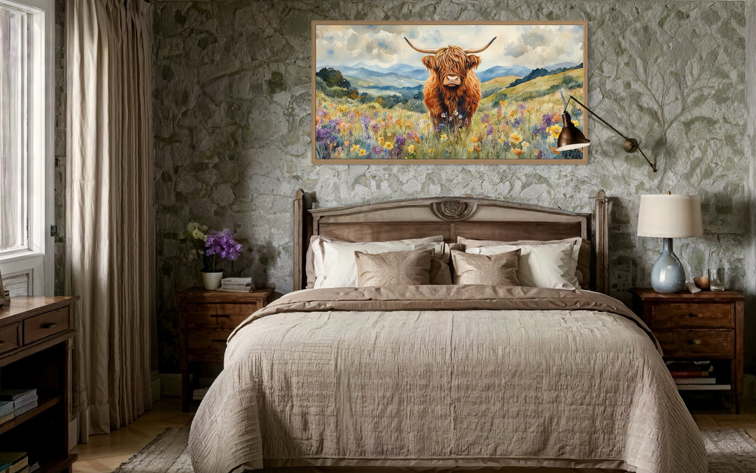 Highland Cow in Wildflower Field framed canvas wall art hanging above a bed in a rustic bedroom.