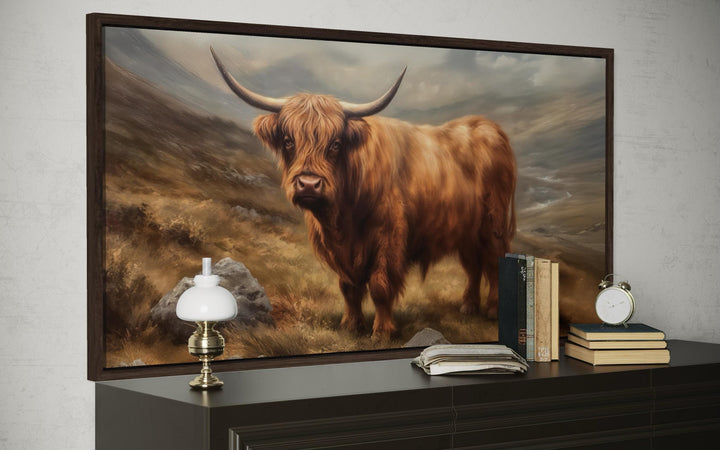 Highland cow rustic farm animal wall art in a dark wood frame above a dresser with vintage books.