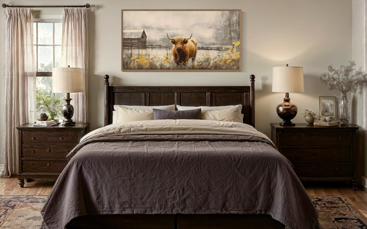 Framed Highland cow canvas wall art hanging above a dark wood bed in a rustic farmhouse bedroom.