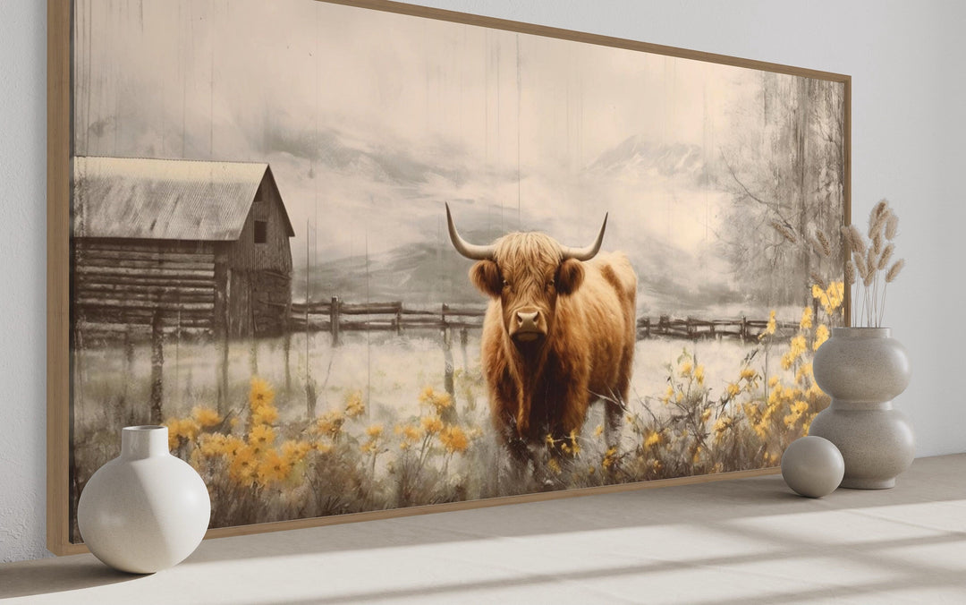 Framed Highland cow canvas wall art featuring a rustic barn and yellow flowers in a country setting.