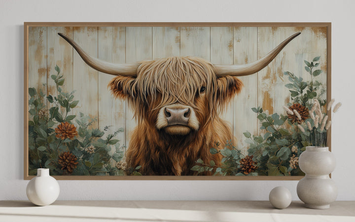 Framed canvas wall art of a Highland cow with flowers on a distressed wood-style background.