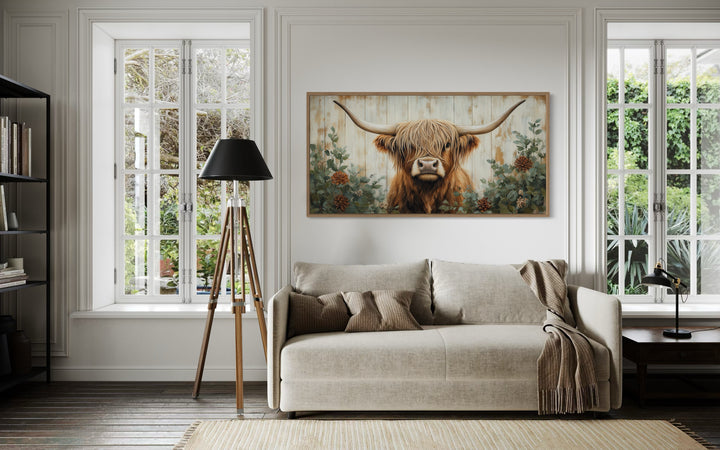Highland cow with flowers on distressed wood framed canvas wall art in a farmhouse living room.
