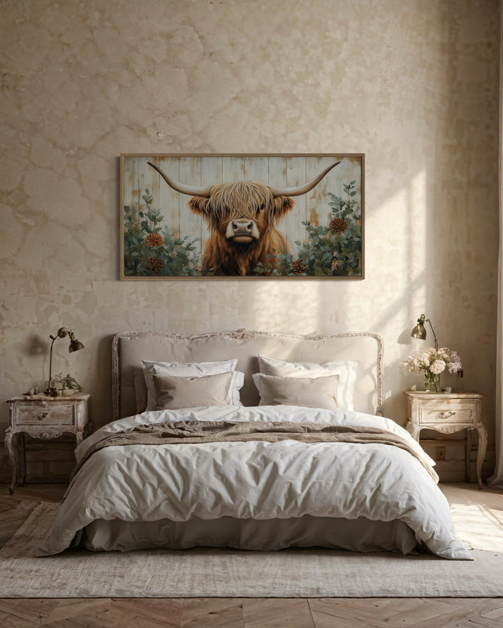 Highland cow with flowers on distressed wood framed canvas wall art above a farmhouse style bed.