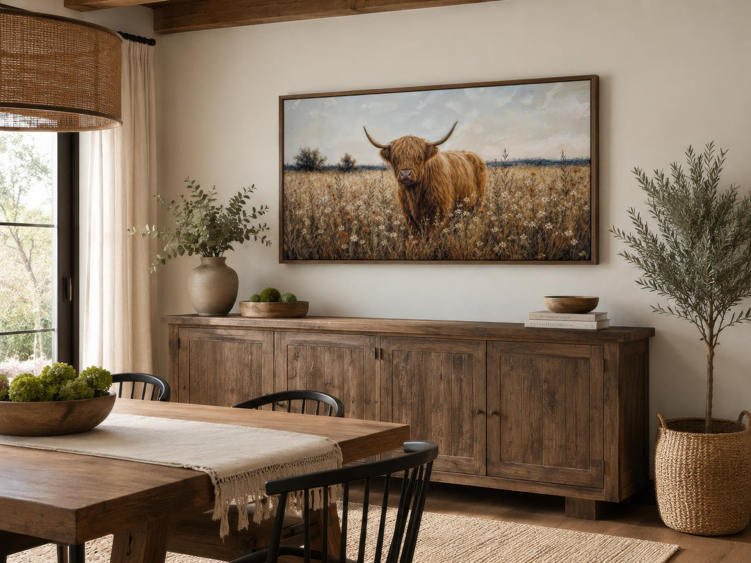 Highland cow in a golden wildflower meadow canvas print above a rustic wood sideboard.