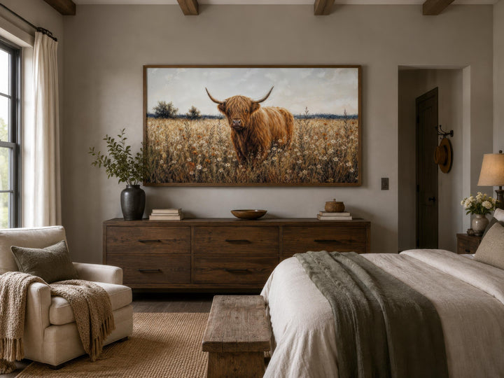Highland Cow in Wildflower Meadow canvas print hanging above a rustic wooden dresser in a bedroom.