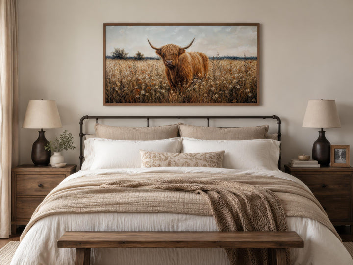 Framed Highland cow canvas print hanging above a bed in a rustic farmhouse bedroom.
