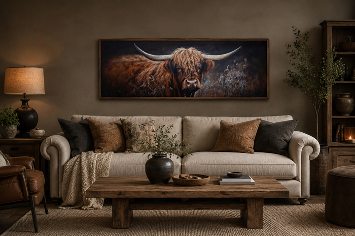 Long horizontal canvas wall art of a dark Highland cow above a sofa in a rustic living room.