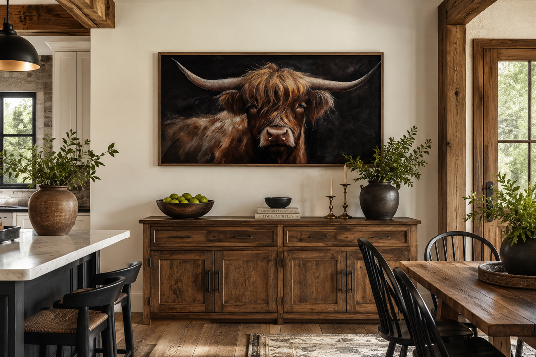 Framed highland cow canvas wall art on a black background above a rustic wooden sideboard.