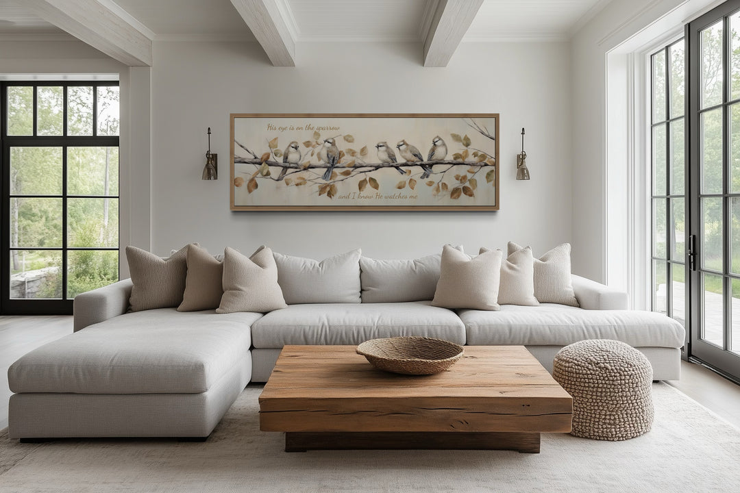 Horizontal framed canvas art of sparrows on a branch with scripture above a neutral sectional sofa.