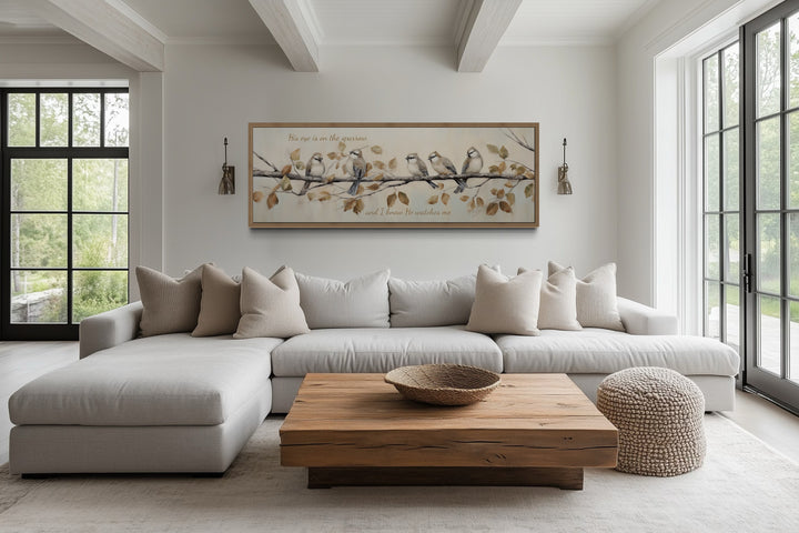 Horizontal framed canvas art of sparrows on a branch with scripture above a neutral sectional sofa.