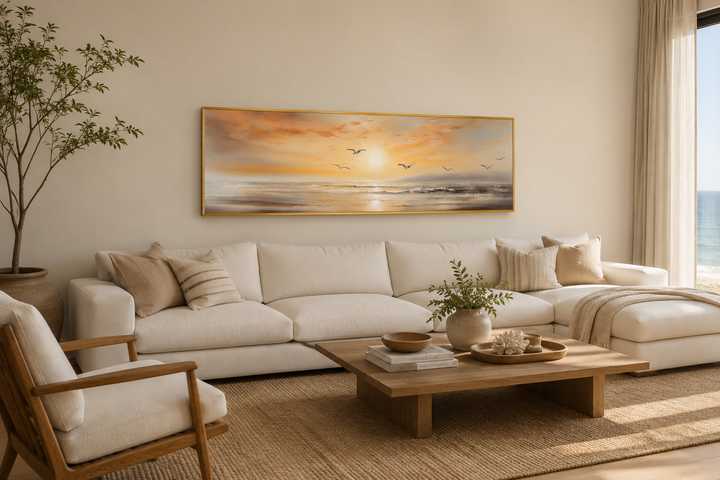 Gold and silver beach sunset seascape with birds narrow horizontal wall art above a white sofa.