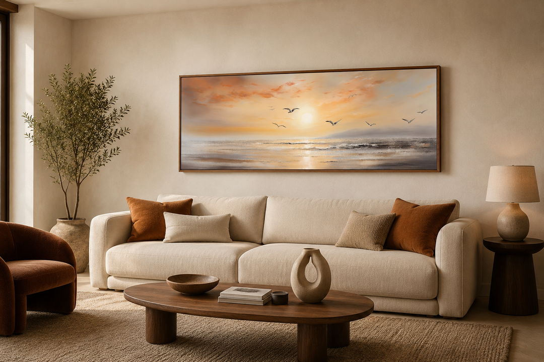 Narrow horizontal wall art of a gold and silver beach sunset with birds above a cream sofa.