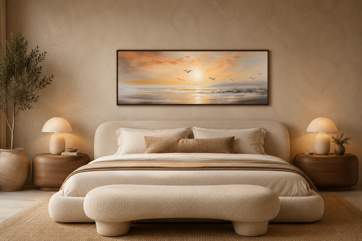 Narrow horizontal wall art of a gold and silver beach sunset with birds above a bed.