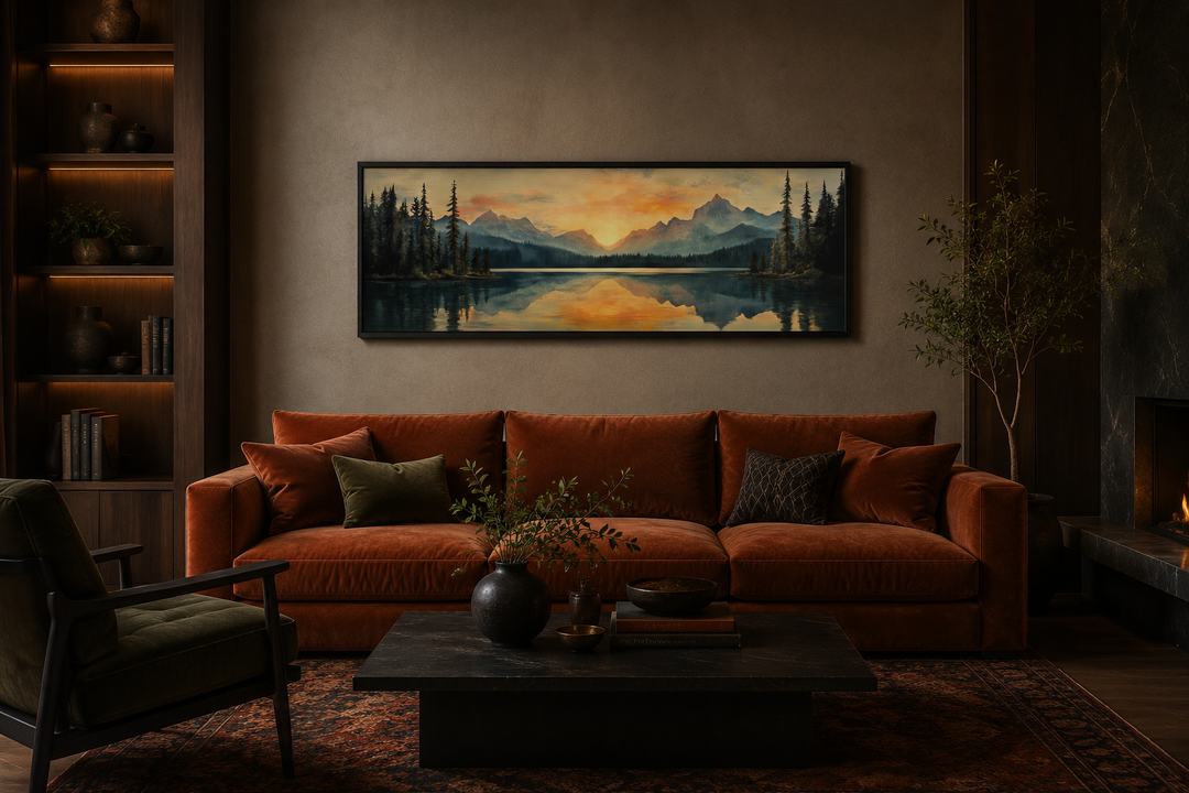 Panoramic mountain lake sunset painting in a black frame above a rust-colored velvet sofa.