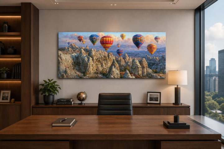 A wide panoramic canvas print of colorful hot air balloons over the Cappadocia landscape in an office.