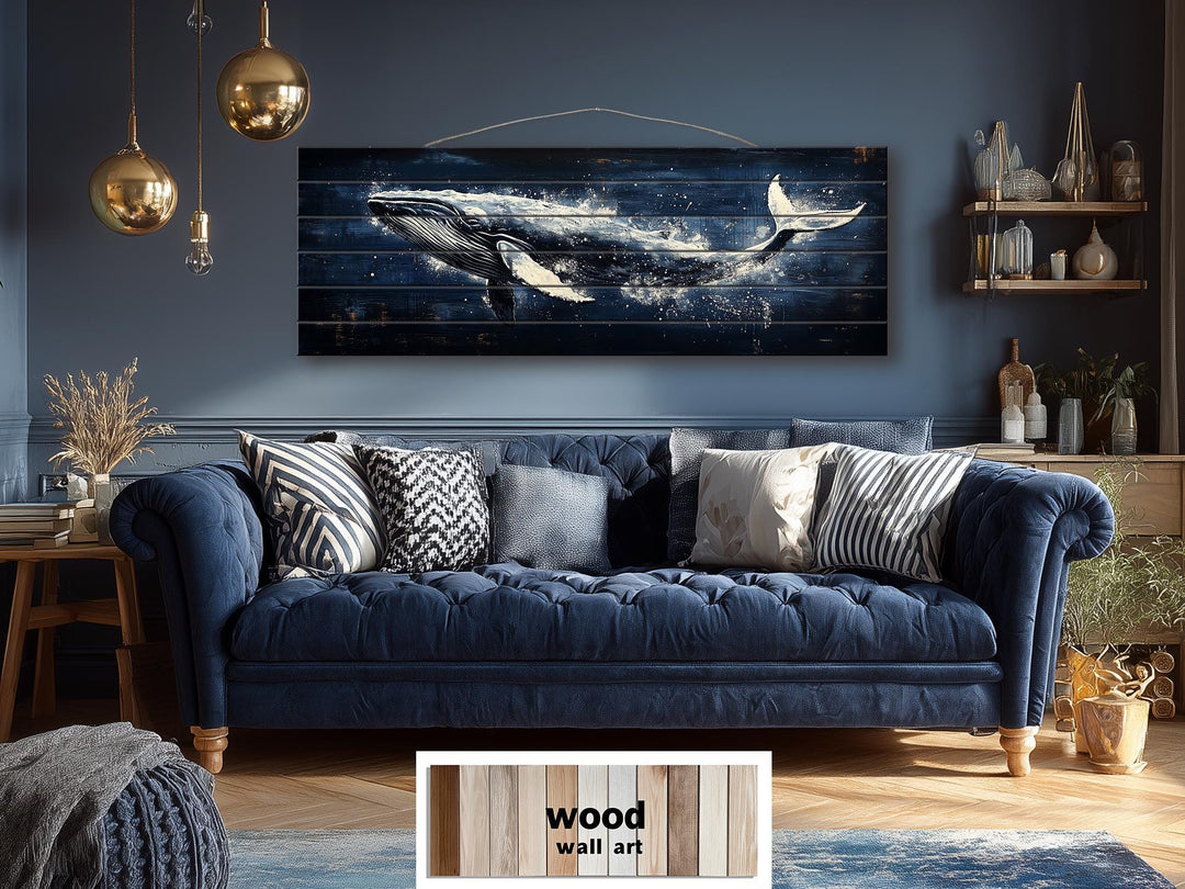 Humpback whale nautical wall art printed on long, narrow distressed wood planks above a blue sofa.