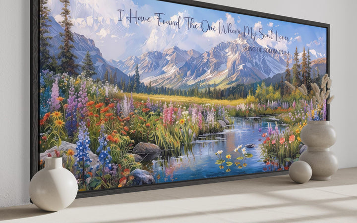 Mountain landscape wall art with wildflowers and Song of Solomon 3:4 scripture in a black frame.