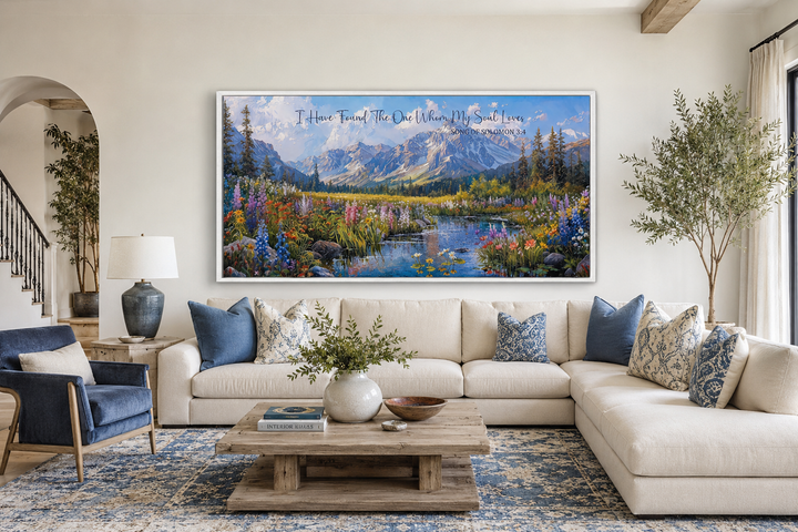 Mountain landscape wall art with Song of Solomon 3:4 scripture above a white sectional sofa.