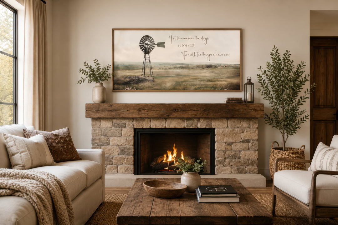Rustic farm landscape wall art with a windmill and quote above a stone fireplace mantel.