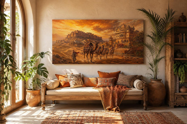 Indian camel caravan painting on a canvas print hanging above a sofa in a warm, bohemian room.