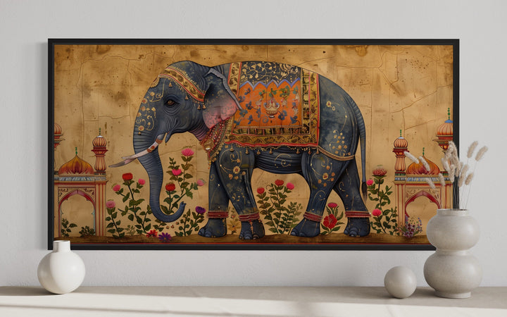 Framed canvas wall art of a decorated Indian elephant with floral motifs on a gold background.