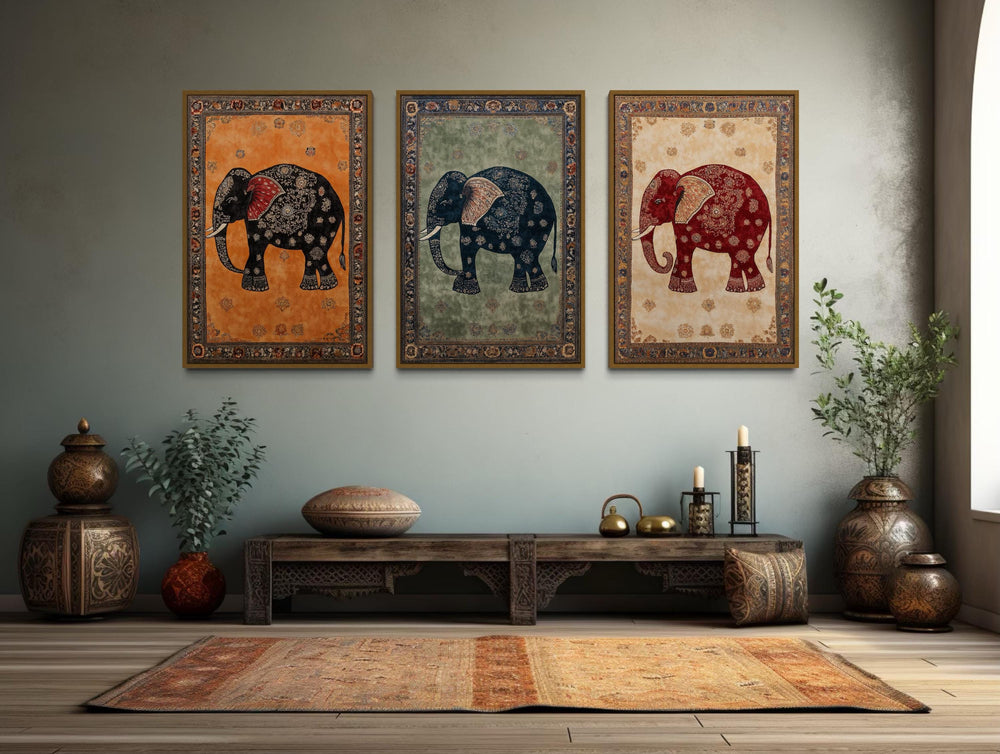 Set of 3 Indian Madhubani elephant canvas prints in orange, green, and cream over a wooden bench.