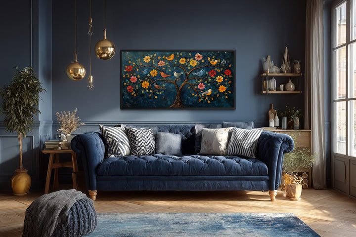 Madhubani Tree of Life canvas wall art with birds and flowers displayed in a dark blue living room.